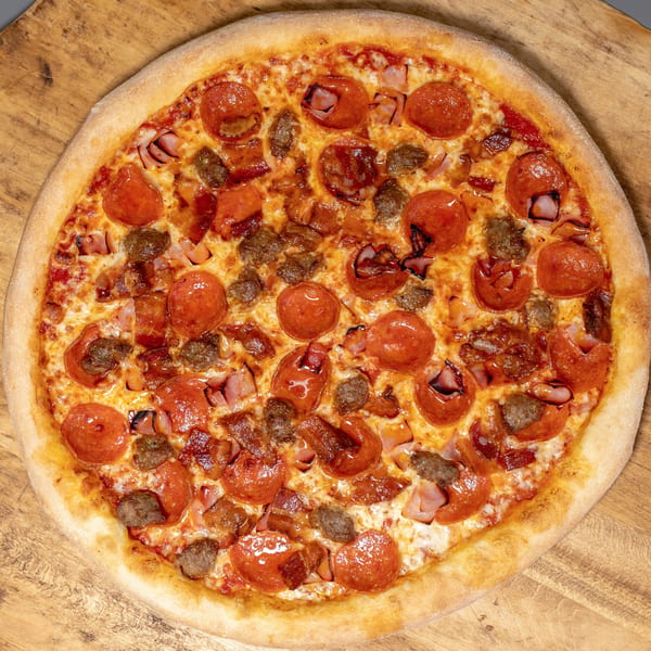 A close-up, overhead view of a whole Uncle Vito's Pizzeria meat lover's pizza on a wooden surface.