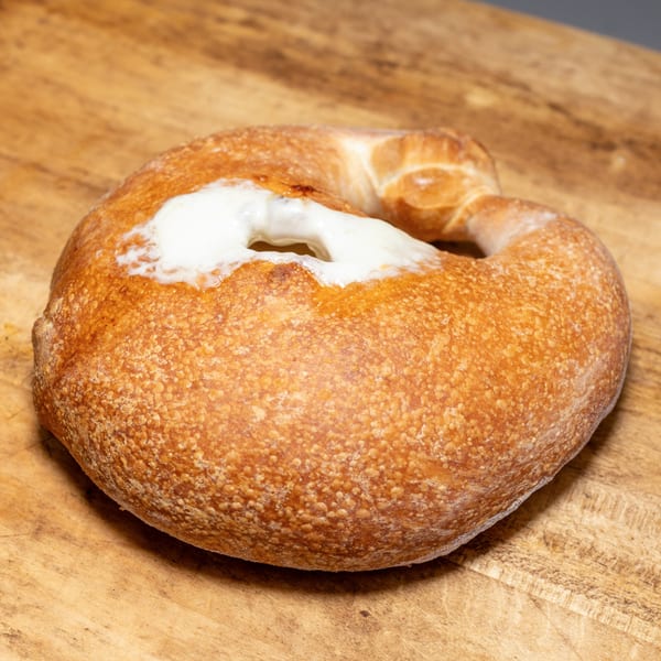 Freshly baked, golden-brown bread with a white, creamy topping on a wooden surface.